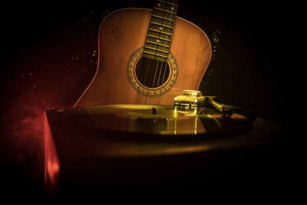 Vintage vinyl record playing on player and acoustic guitar on background with fire orange smoke. Blues concept. With Toy car. Selective focus