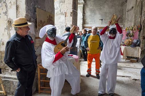 Naples, Italy - May 23, 2015: Neapolitan Mask of Pulcinella Playing and Singing in the Street of Santa Chiara in Naples city heart, people around looking at singers!