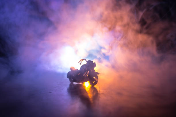 istock High power motorcycle chopper. Fog with backlights on background with man rider at night. Empty space 960798736