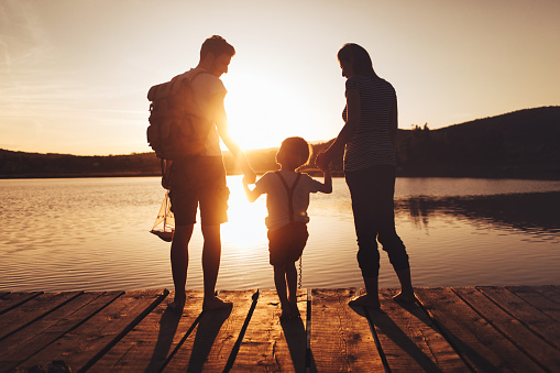 Photo of a young family spending some quality time together on a lake dock at sunset