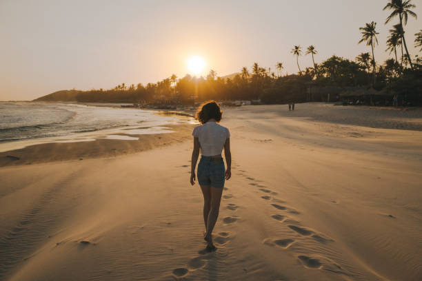 Rear view of carefree woman having fun during her summer vacation on the beach at sunset. Copy space.