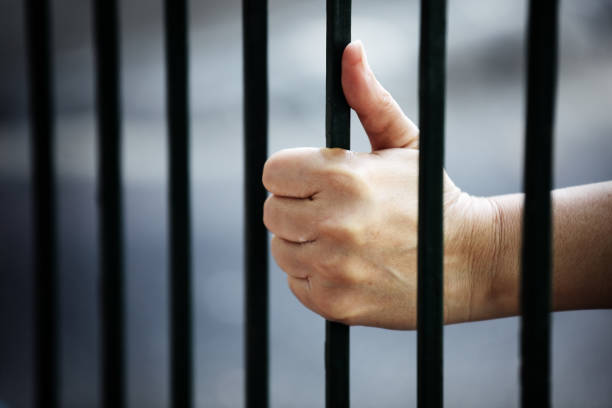 istock close up of prisoner hands in jail background. 960830912