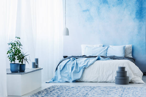 istock Sky blue bedroom interior with double bed, plants and grey boxes on the floor 960834282
