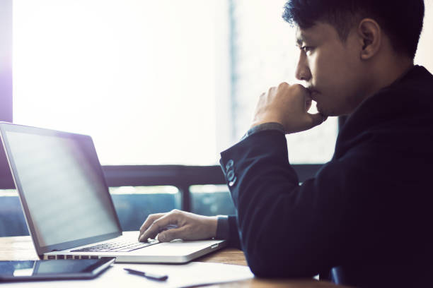 istock Young asian businessman working on his computer in his office near large bright window, selective focus and blur color toning, good for business theme or concept 960834322