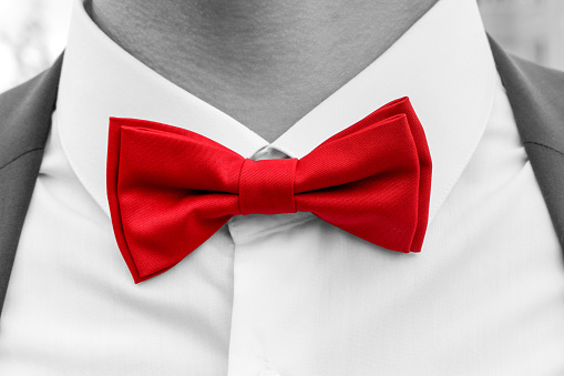 Red bow tie on neck of man, black and white photo with coloured element