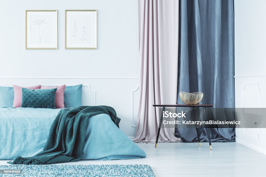 Two posters above bed Two simple posters in gold frames hanging on the wall above double bed standing in bright room with drapes Curtain Stock Photo