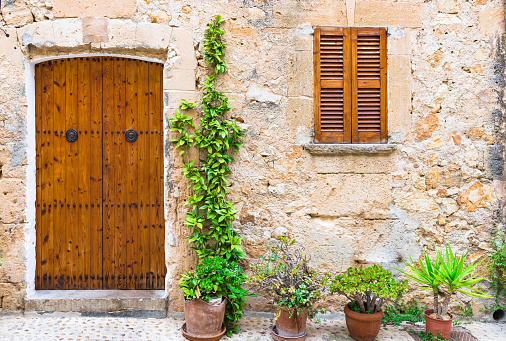 Mediterranean house door and window with flower pots in front of wall
