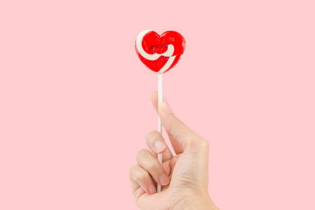 istock Hand holding red lollipops heart shape isolated on pastel pink background with clipping path inside. 960859132