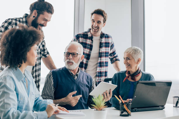 istock Senior man with digital tablet sharing office with coworkers 960865818