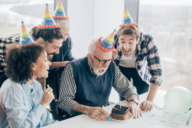 istock Birthday man blowing candles on birthday cake at office 960865980
