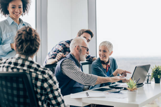 istock Happy business people talking and pointing towards laptop 960865984