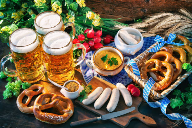 Bavarian sausages with pretzels, sweet mustard and beer mugs on rustic wooden table stock photo