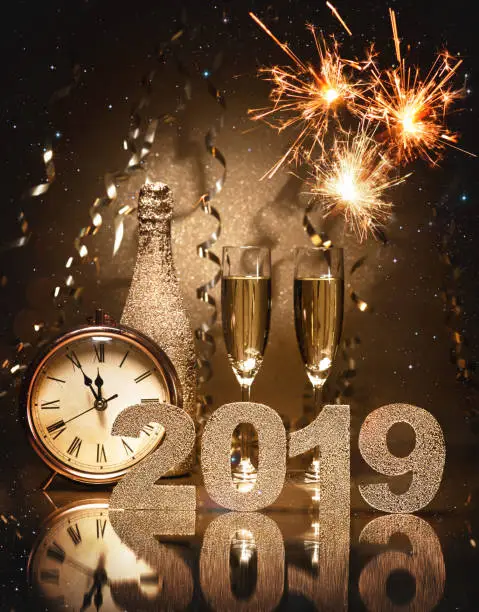 New Years Eve celebration background with pair of flutes, bottle of champagne and a clock