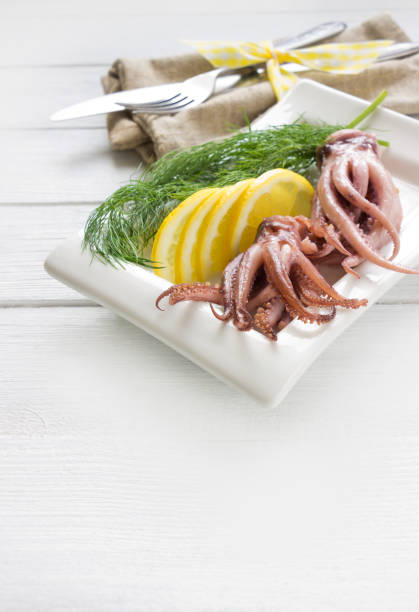 istock Squid tentacle with lemon and dill on white plate on white wooden board .Seafood restaurant menu 960871942