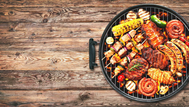 Assorted delicious grilled meat and bratwurst with vegetables on grill Assorted delicious grilled meat and bratwurst with vegetables over the coals on a barbecue on rustic wooden background coal photos stock pictures, royalty-free photos & images