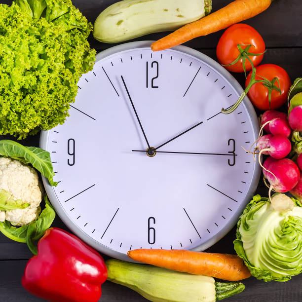 istock Clock and fresh vegetables. Zucchini, bell peppers, carrots, cabbage, cauliflower, radish, lettuce, tomato. Concept of a healthy diet. Copy space. 960875370