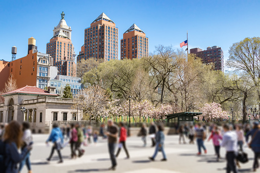 Anonymous crowd of people walk through Union Square Park on a sunny spring day in Manhattan, New York City NYC