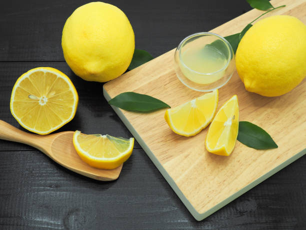 istock Fresh lemon juice in small bowl and lemon slice on dark wood background 960897632