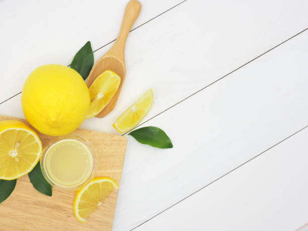 istock Fresh lemon juice in a small bowl and lemon slice on white wood background 960897904