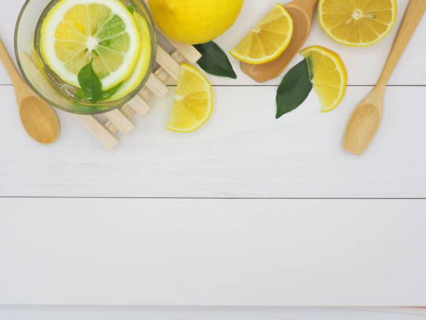 istock Fresh lemon in water and lemon slice on white wood background 960907578