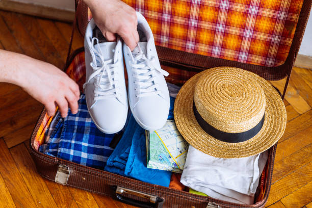 istock hands put sneakers to valise. packing for trip. travel concept 960911424