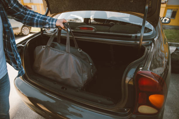 istock man put bags to car trunk. car travel concept 960916632