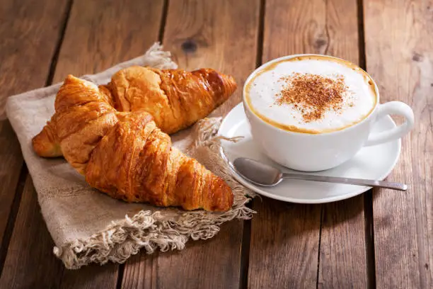 Photo of Cup of cappuccino coffee with croissants