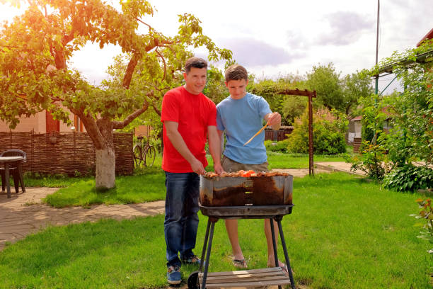 istock Attractive white father and son are smiling and grilling kebabs 960946266