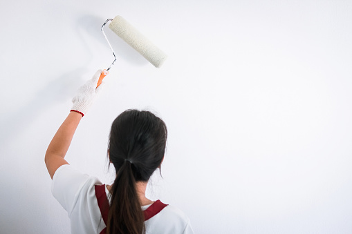 Interior working, Painter hand in white glove painting wall with paint roller in room, shape and structure.