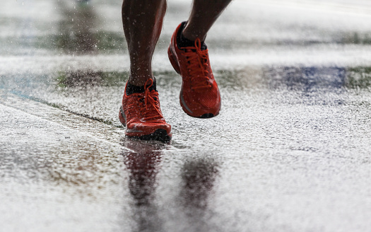 Closeup of legs in sports shoes running in the rain