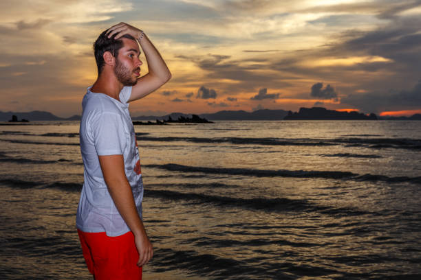 Young man posses at Ao Nang Beach, Krabi, Thailand at sunset