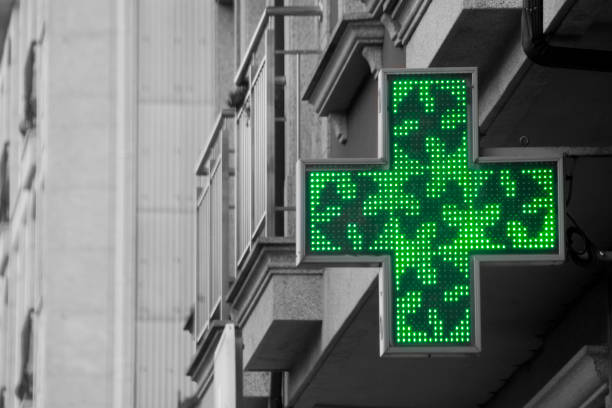 simbolo della farmacia per strada, edifici alti, croce verde. - green cross foto e immagini stock