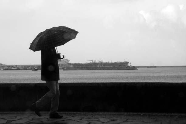 Man sitting alone with umbrella looking at the beach in the distance