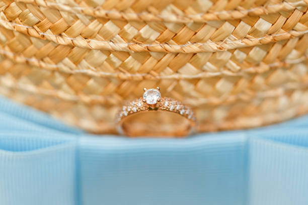 istock Golden engagement ring with diamonds lying on the canotier hat 960986178