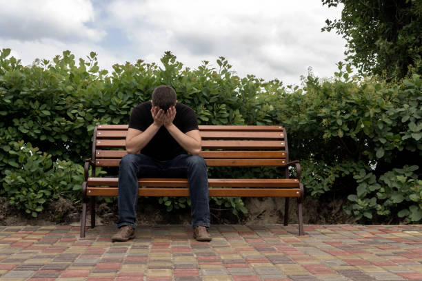 the guy is sad in the park on the bench