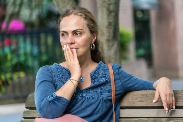 Hispanic woman looking away sitting in a bench