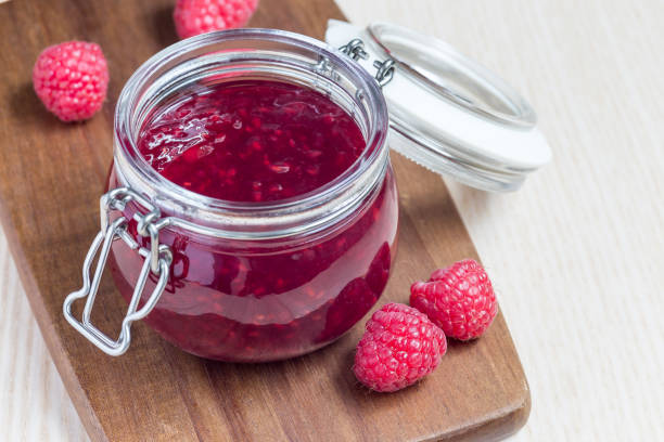 istock Raspberry jam in glass jar on a wooden board, horizontal, copy space 961026424