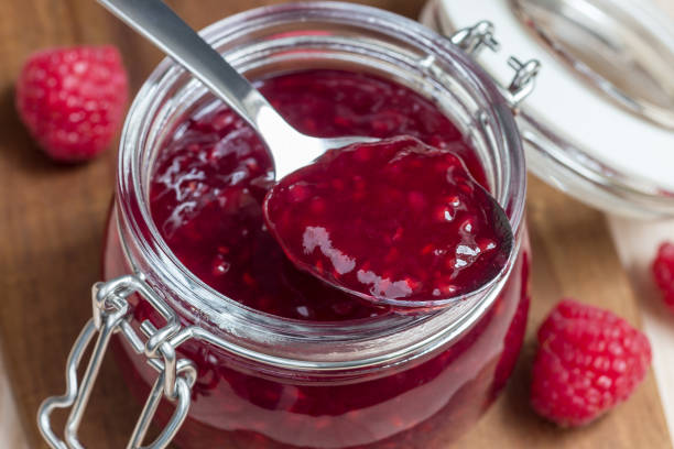 istock Raspberry jam in glass jar on a wooden board, horizontal 961026486