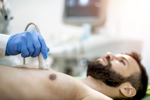 Sick mid adult man having his chest examined by ultrasound technology.