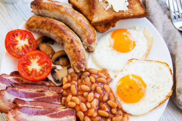 istock English breakfast with fried eggs, bacon, sausages, beans and toasts. Closeup. 961032430