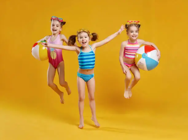 Photo of funny funny happy children  jumping in swimsuit  jumping  on colored background