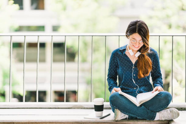 młoda azjatycka studentka czytania książki do egzaminu, siedząca na kampusie uniwersyteckim z kopią miejsca. edukacja lub dorywczo studiowanie koncepcji stylu życia - college student student asian ethnicity high school student zdjęcia i obrazy z banku zdjęć