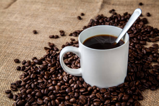 istock White coffee mug with coffee beans on hessian sack cloth 961060700