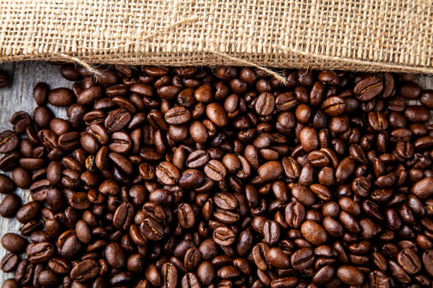 istock Dark roasted coffee beans with a hessian or jute natural colour sacking 961060816