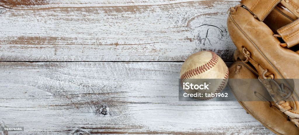 Flat lay view of old baseball and mitt on white rustic wooden boards Overhead view of baseball and mitt on white vintage wood Baseball - Sport Stock Photo