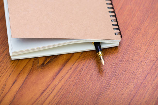 istock Fountain pen or ink pen with notebook paper on wooden working table with copy space, office desk concept. 961077914