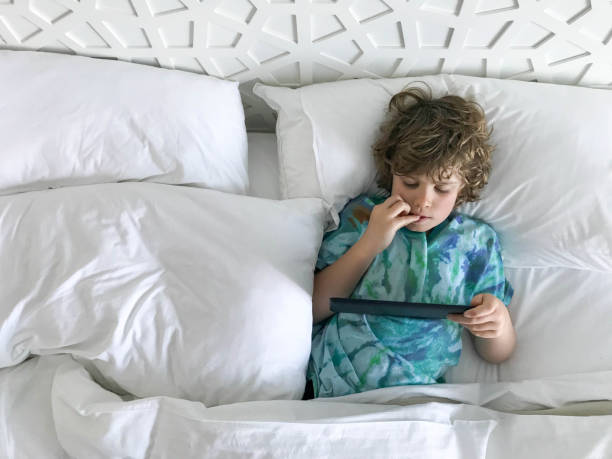 ребенок, использующий планшет в гостиничном номере в утреннем свете - child beach digital tablet outdoors стоковые фото и изображения