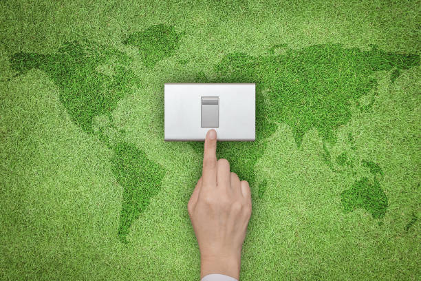 istock Energy saving and ecological friendly concept with hand turning off switch on green grass lawn with world map 961080774