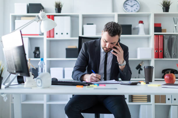 istock A man is sitting in the office at the table, talking on the phone and working with documents. 961081090
