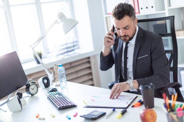 istock A man is sitting in the office at the table, talking on the phone and flipping through documents. 961081100
